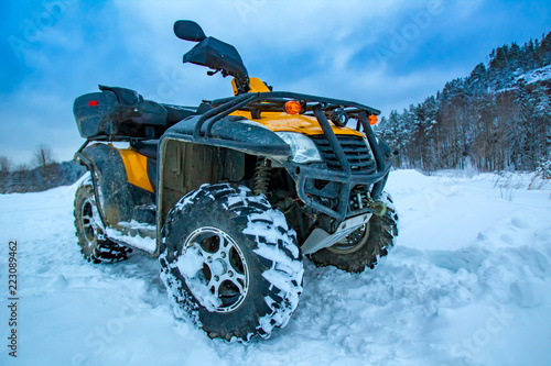 ATV  is a yellow color. ATV rentals. Quad bike on the background of the mountain. SUV. Traveling in winter on an off-road car. Quad bike against the snow.
