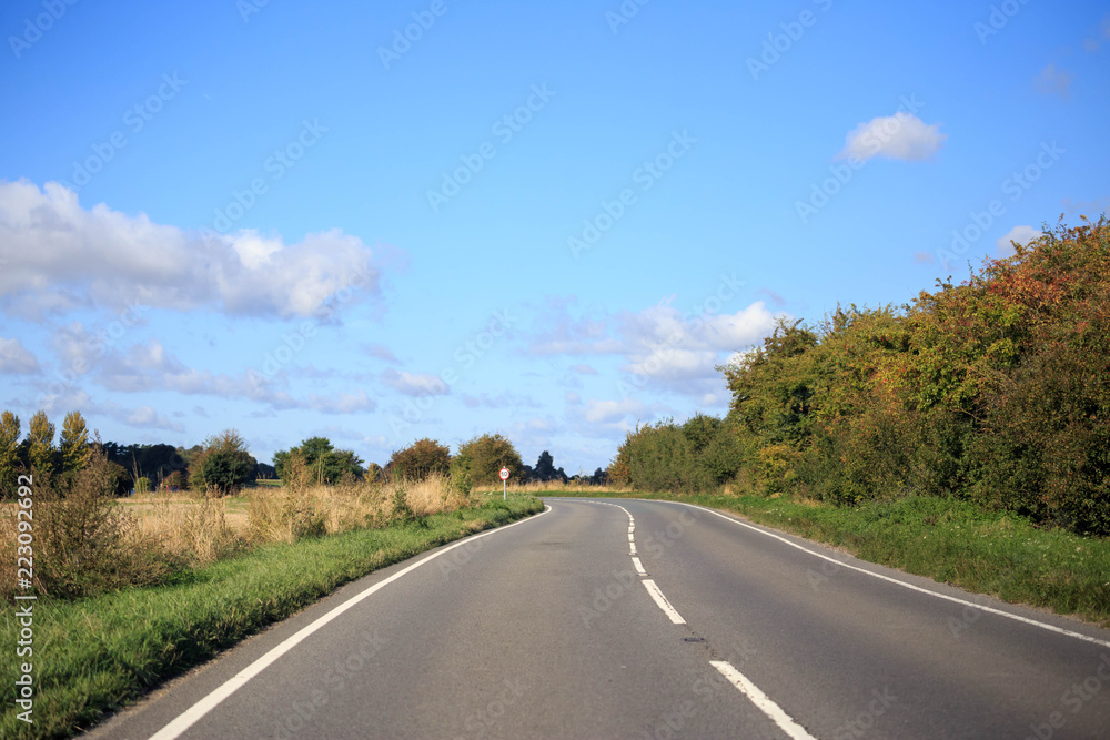 Idyllic country road curves through the English countryside on sunny day