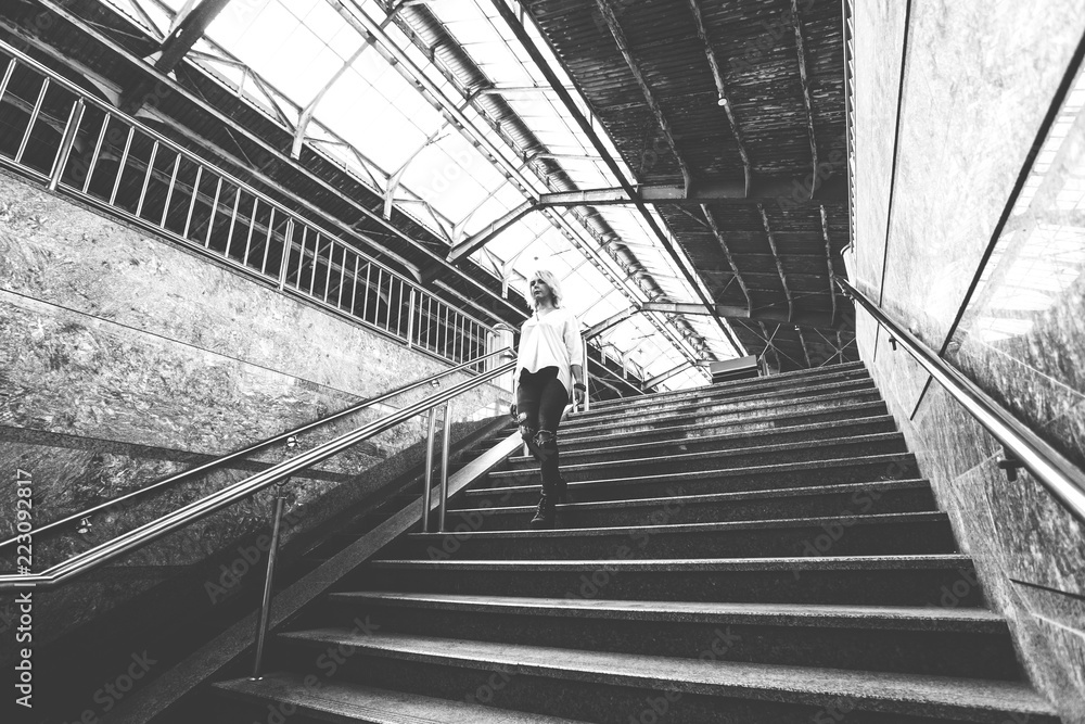 beautiful young girl in jeans and a white blouse goes down the stairs, black and white photo, retro toned