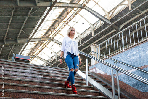 beautiful young girl in jeans and a white blouse goes down the stairs
