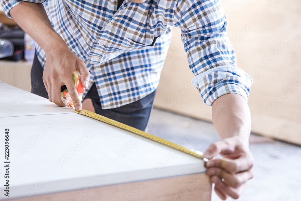 Obraz premium young carpenter measuring the furniture