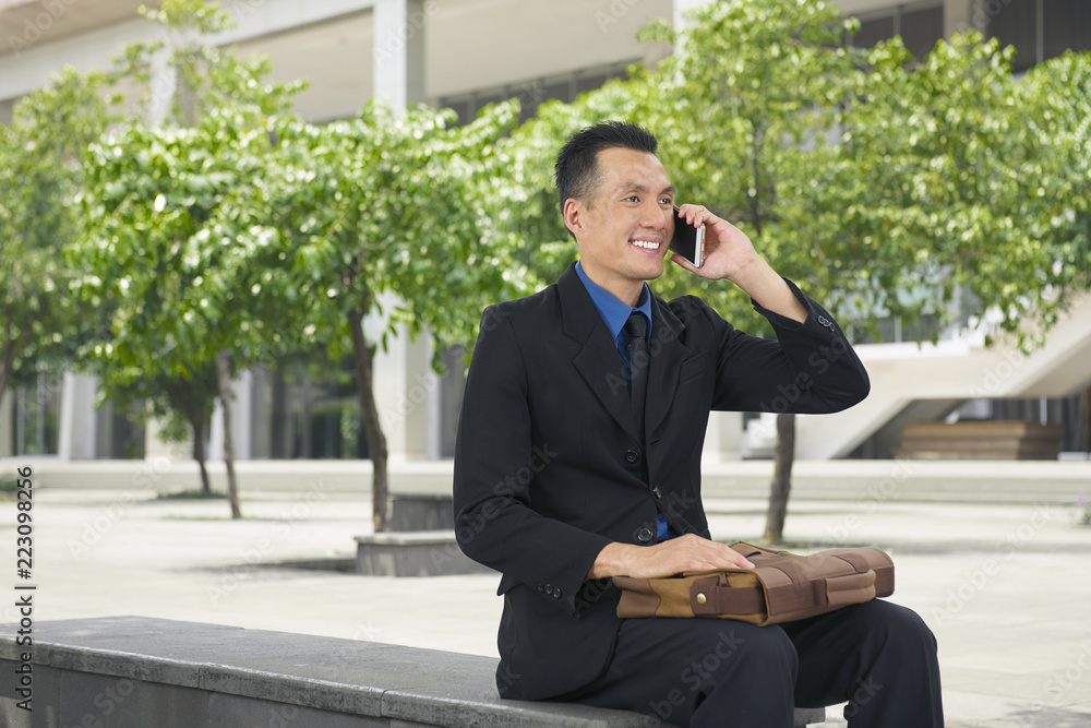 Handsome asian businessman talking on his cell phone Handsome asian businessman talking on his cell phone