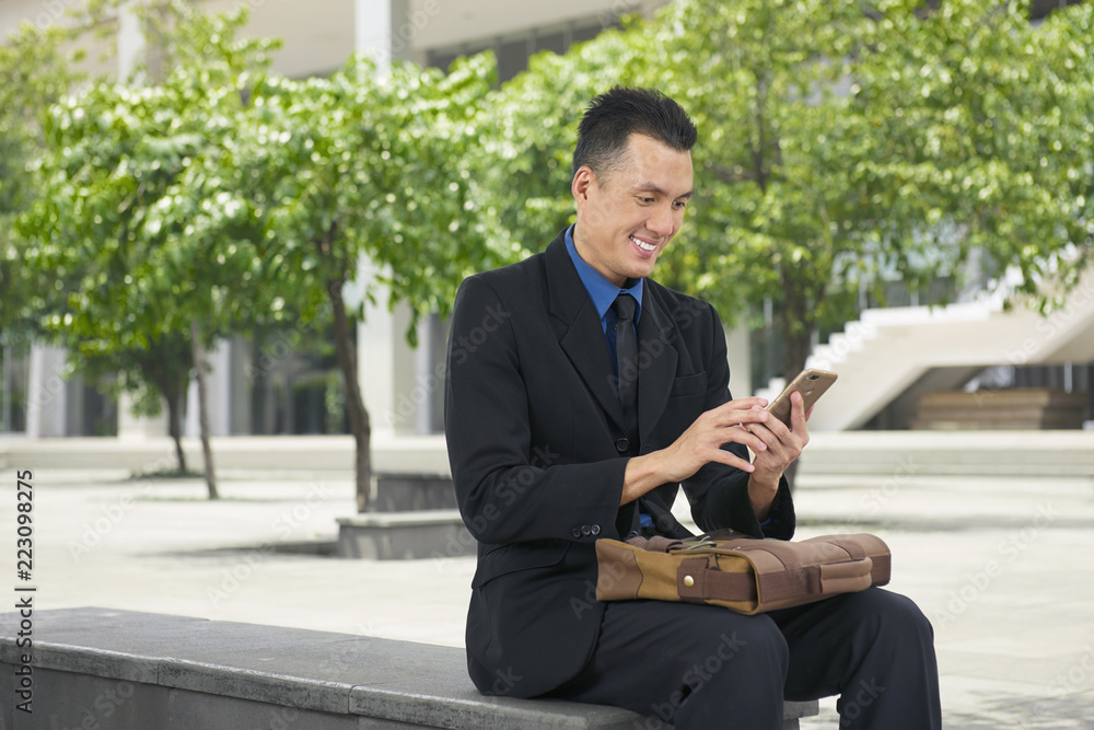 Smiling asian businessman using mobile phone Smiling asian businessman using mobile phone