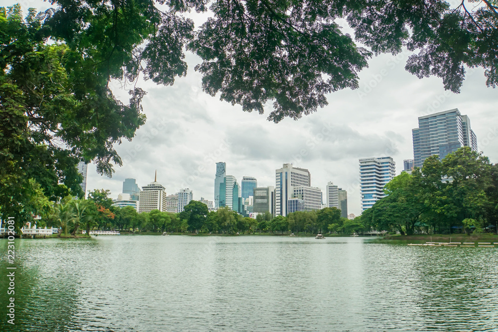 Lumpini Park Bangkok / Thailand: August 1 2018: clean canal with shade from green big trees in park with skyscrapers backdrop