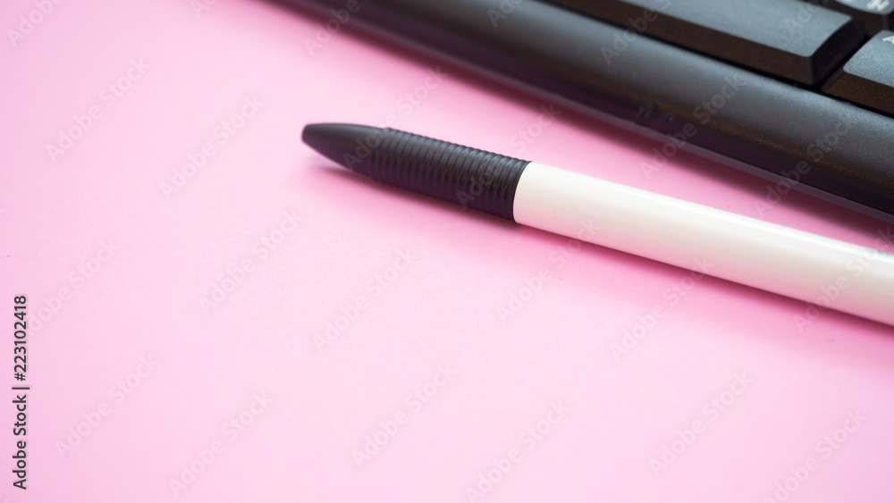 pen close up and black keyboard on pink background pen close up and black keyboard on pink background