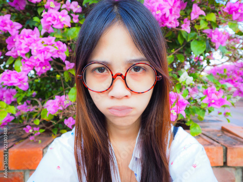 A women wearing red glasses and have trance feeling with bushes background