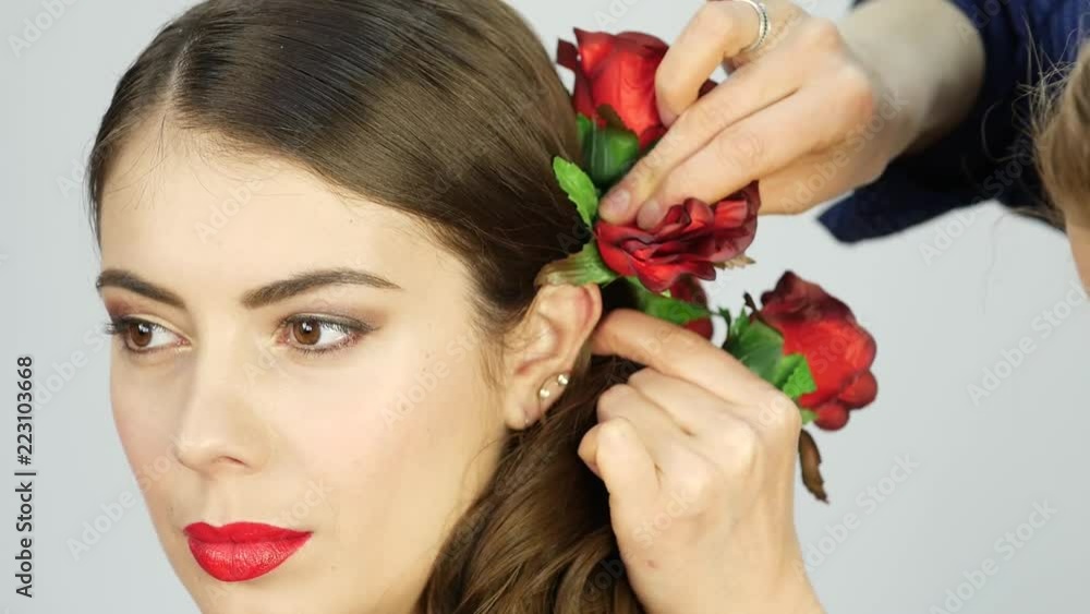 Hairstylist, hairdresser finishing creative hairstyle with flowers for beautiful girl Hairstylist, hairdresser finishing creative hairstyle with flowers for beautiful girl