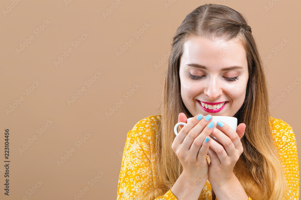 Young woman drinking coffee on a brown background Young woman drinking coffee on a brown background