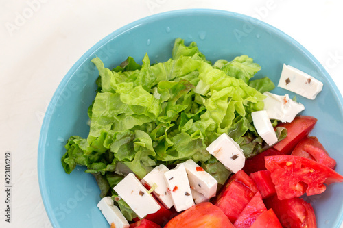 Useful food in a blue plate. Easy appetizer from vegetables and feta cheese for breakfast, lunch or dinner. Tomatoes and salad. Dietary food. photo