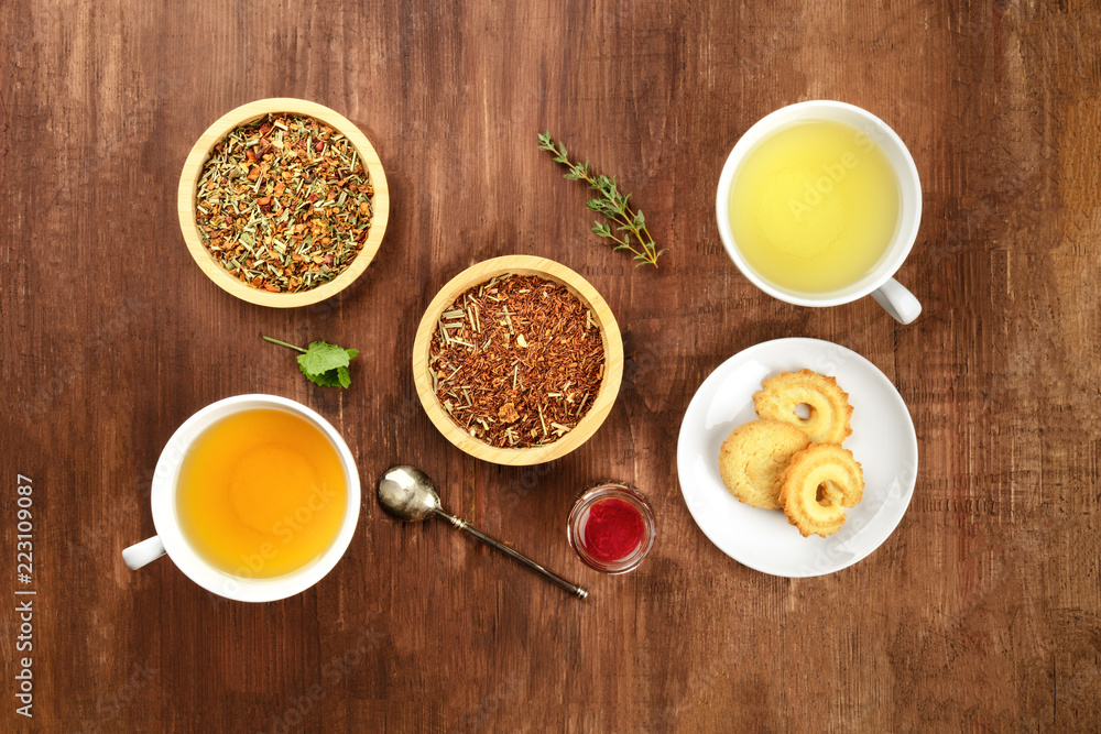 Tea tasting. Various cups of tea and leaves of loose tea with biscuits and jam Tea tasting. Various cups of tea and leaves of loose tea with biscuits and jam