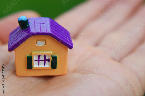 Hand holding little colorful house closeup view with copy space for text. Real estate, buying and moving new home concept. photo