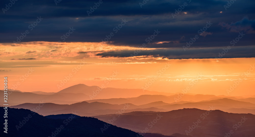 Amazing sunset in the mountains - beautiful golden light peaking through storm clouds with vivid colors and picturesque scenery - perfect relaxation spot