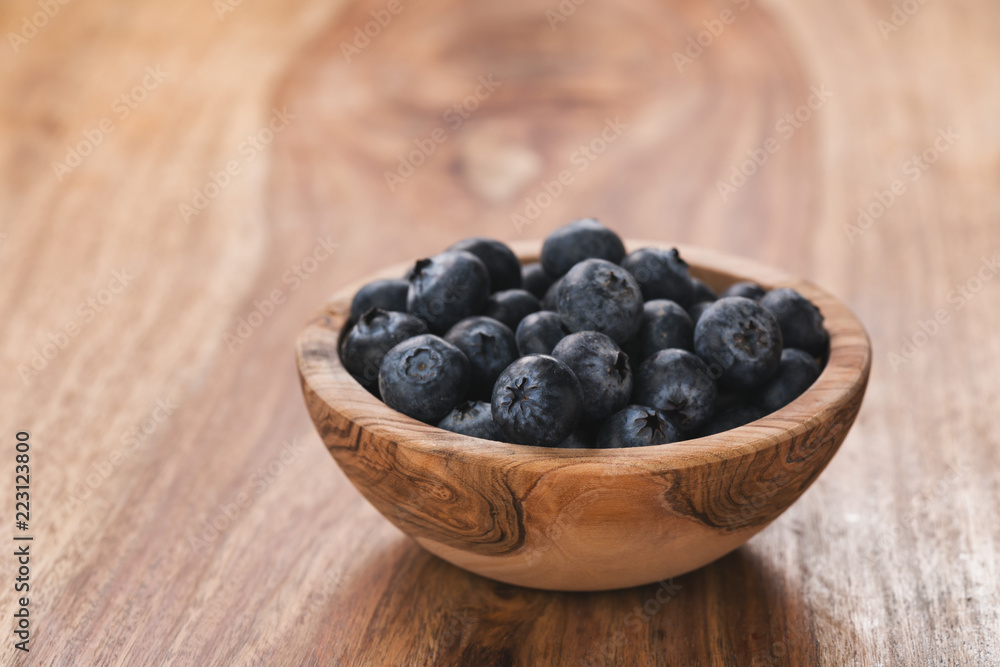 Fresh blueberries in wood bowl on table slightly toned Fresh blueberries in wood bowl on table slightly toned