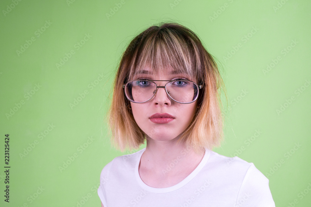 Portrait of a beautiful girl in glasses with short blond hair.