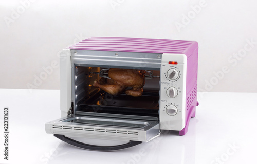 Opened electric oven with chicken inside