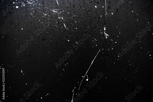 Texture of white paint on a black wall, graffiti, street art. Traces of paintbrush and brush