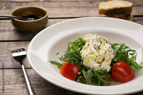 Salad with tomatoes and arugula dressed with white dressing