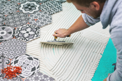 worker applying tile adhesive on the floor