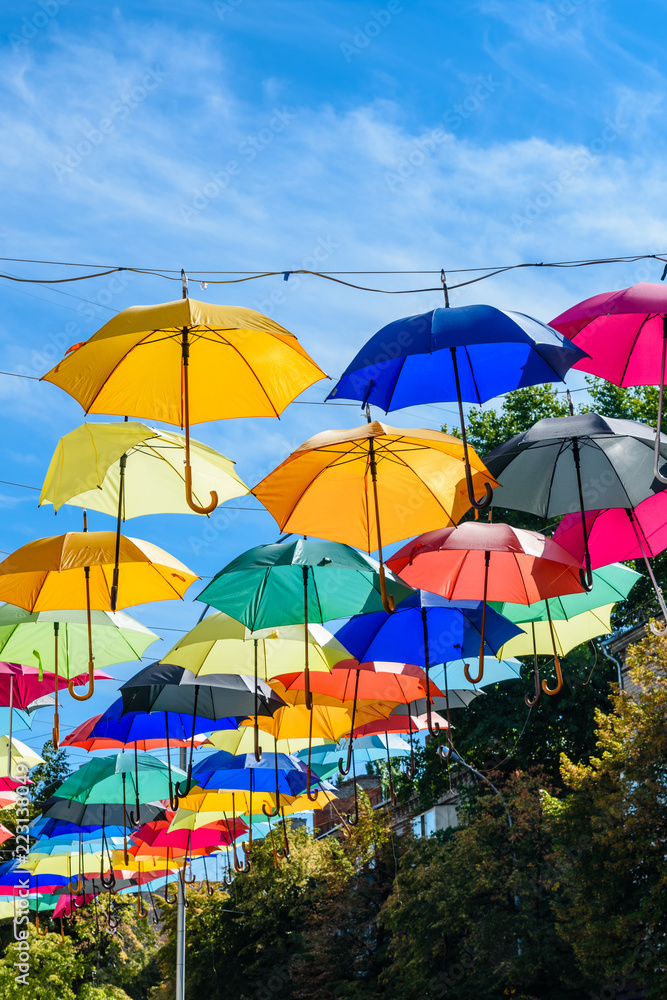 Different colorful umbrellas hanging over the street against sky