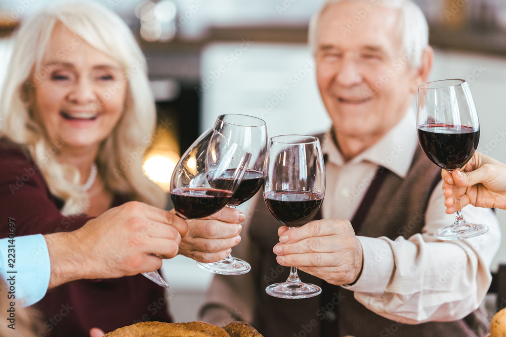 senior couple clinking glasses with family during holiday celebration senior couple clinking glasses with family during holiday celebration
