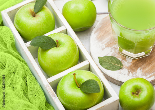 Canvas Print Glass of fresh organic apple juice with granny smith green apples in box on wood