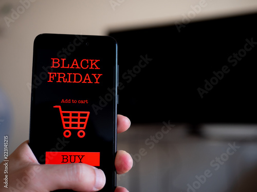 Hand holding phone with black friday app to buy a television. Shopping online. First person point of view