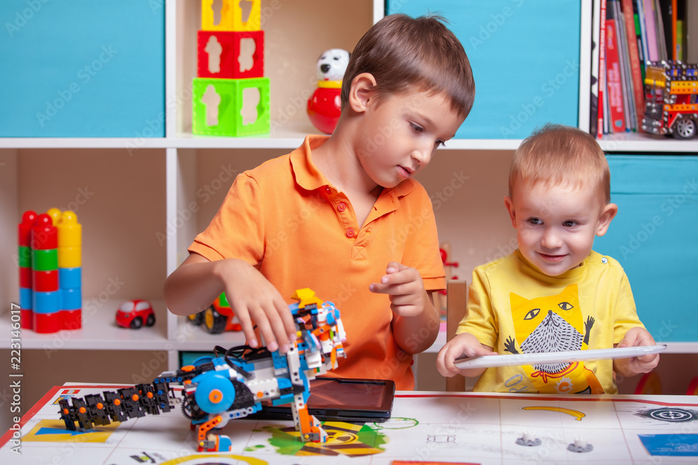 Fototapeta premium Two boys ?hild collects robot from the plastics details
