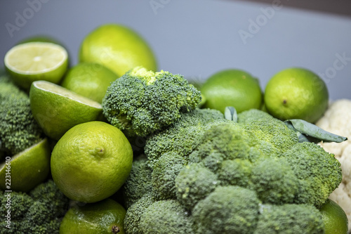 Full and cut lemons in a basket alongside with broccoli
