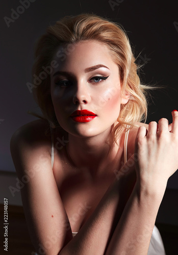 Portrait of a beautiful young girl with blond wavy hair and with red lips and black arrows in retro style.