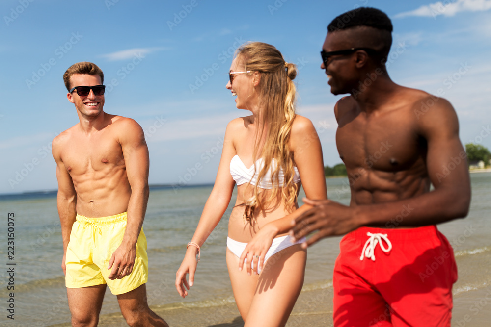 friendship, summer holidays and people concept - happy friends walking along beach friendship, summer holidays and people concept - happy friends walking along beach