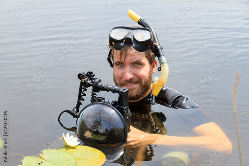 Very handsome young man in a river with water lilies in Rijpwetering, the Netherlands, with equipment for underwater photography on July 19, 2014 photo