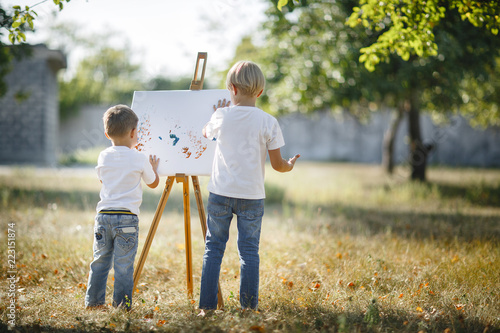 Two unrecognizable children drawing outdoors
