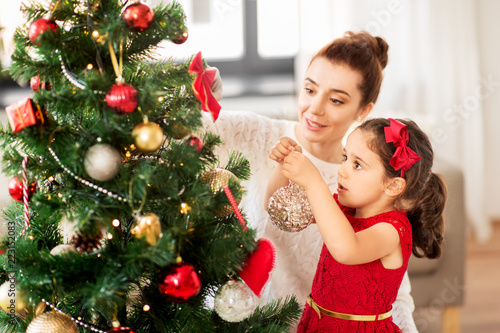 Obraz na plátně family, winter holidays and people concept - happy mother and little daughter de