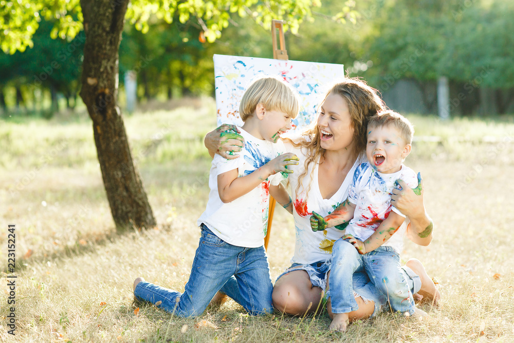 Happy family drawing outdoors. Young mother having fun with her little children Happy family drawing outdoors. Young mother having fun with her little children