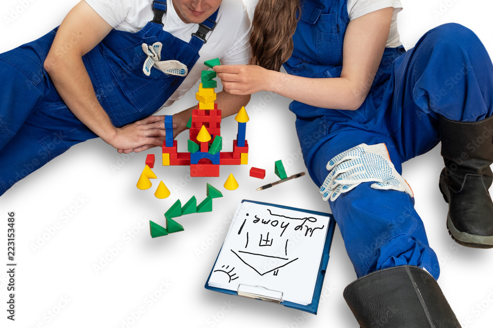 Obraz premium A young couple plans to build a house. Young couple with baby cubes playing in building a house. People in overalls play children's toys in building a house.