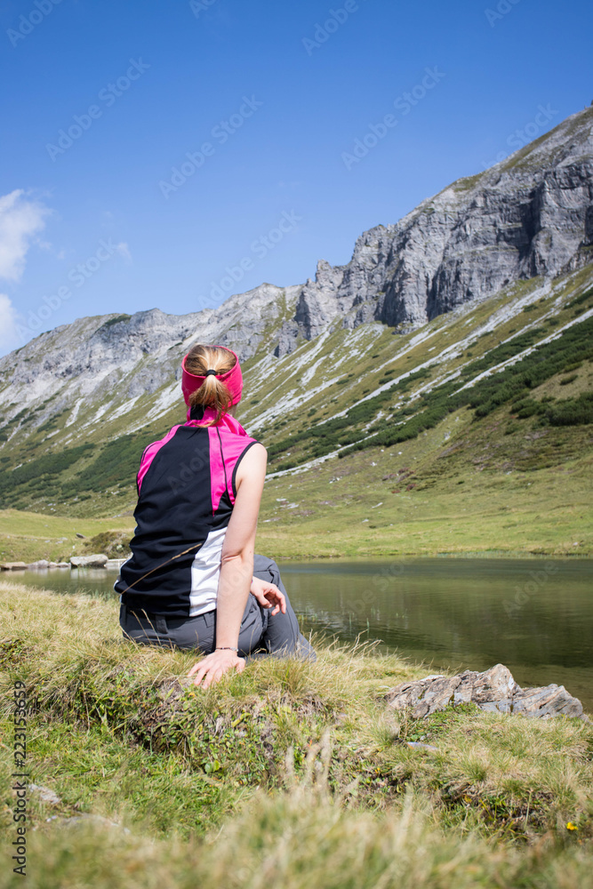 Naklejka premium Junge blonde Frau rastet am Ufer eines Bergsees, Österreich