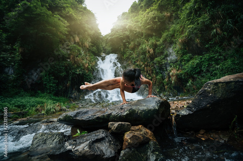 Young woman practice yoga near waterfall in forest © lzf