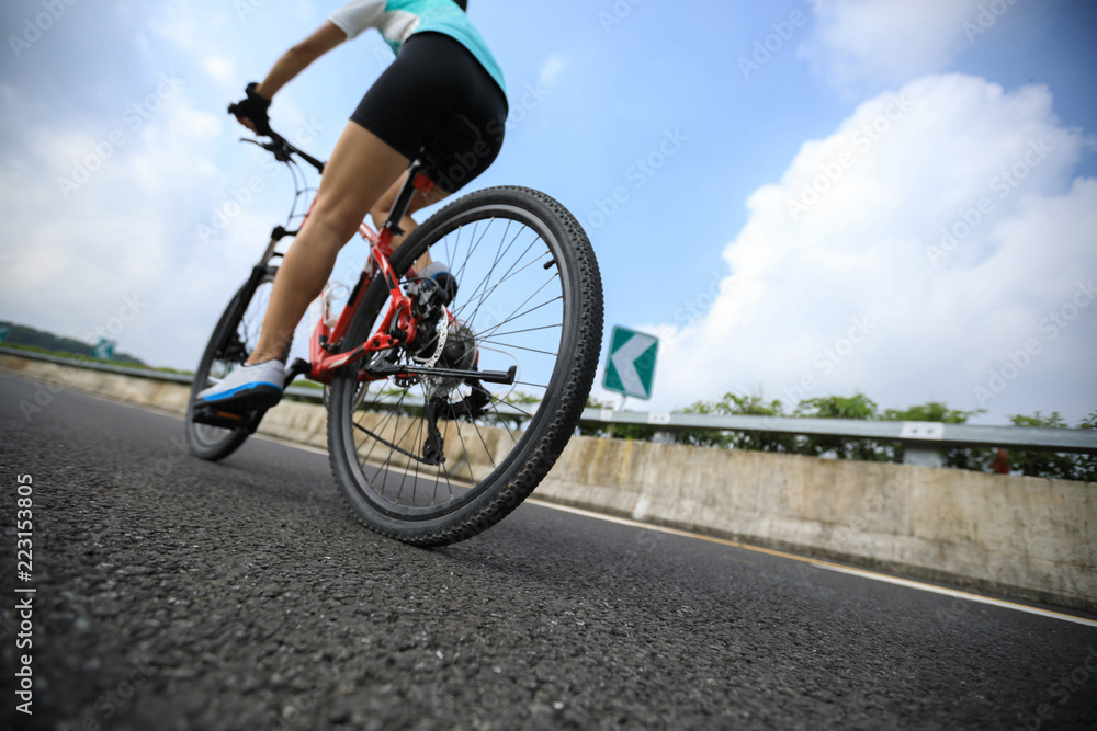 Woman cyclist riding Mountain Bike on highway Woman cyclist riding Mountain Bike on highway