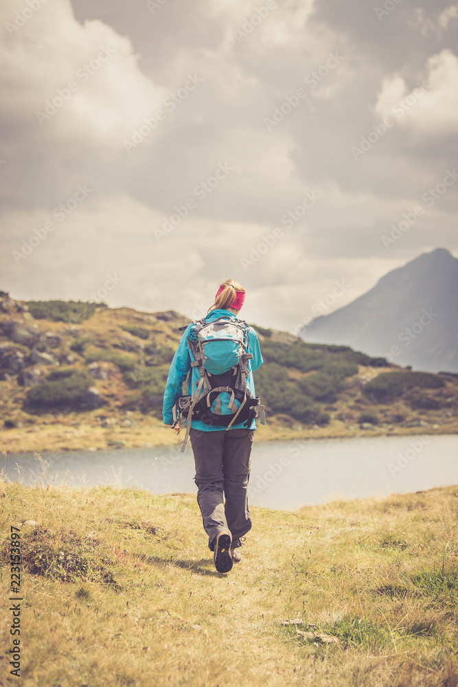 Junge Frau mit Rucksack wandert in den Alpen, Alpensee Junge Frau mit Rucksack wandert in den Alpen, Alpensee