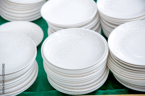 stack of many white plates on the table to prepare for catering buffet. tableware for lunch and dinner. selfservice  buffet. image for background, wallpaper and copy space.