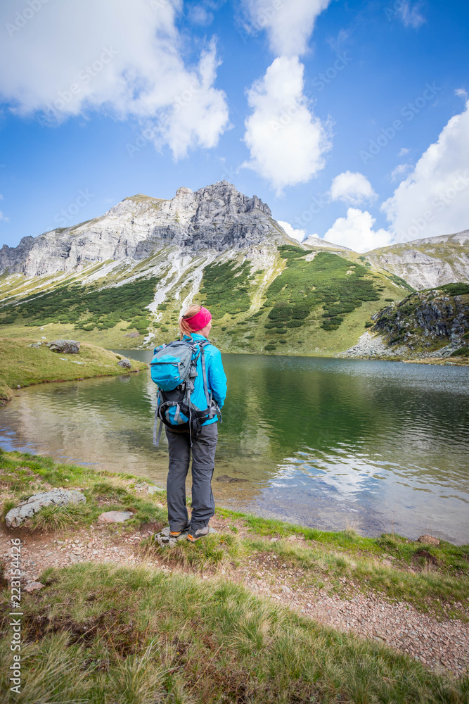 Junge blonde Frau betrachtet die Landschaft in den Berge, Bergsee und Gipfel