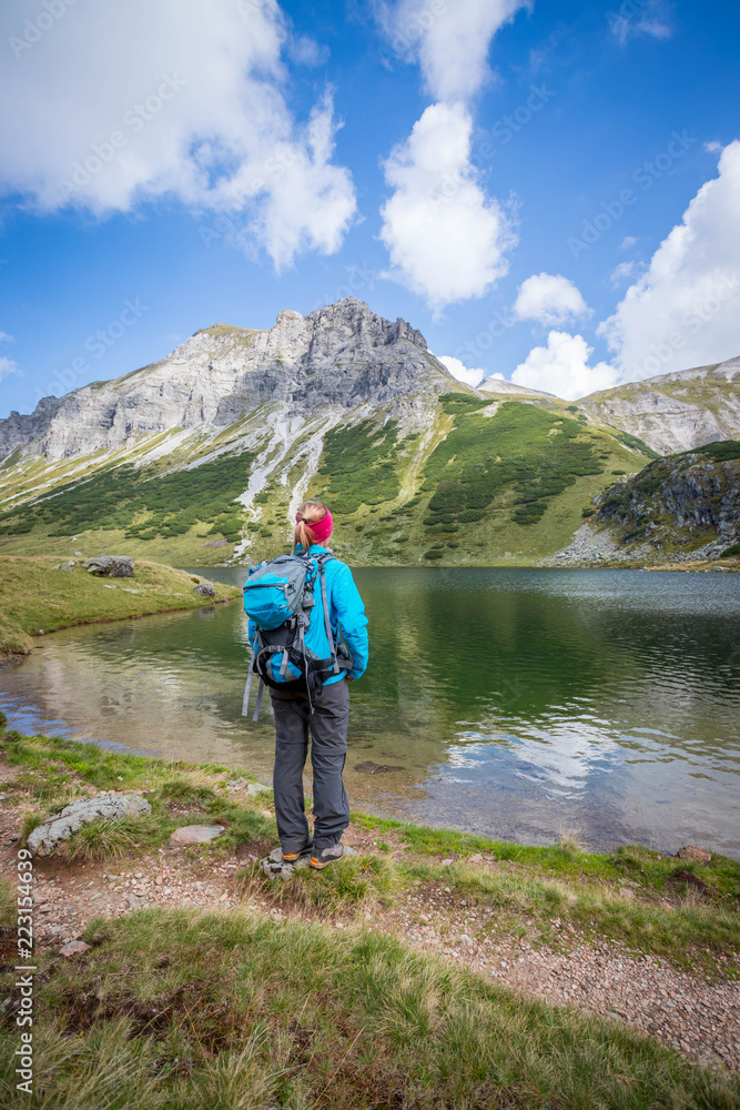 Junge blonde Frau betrachtet die Landschaft in den Berge, Bergsee und Gipfel