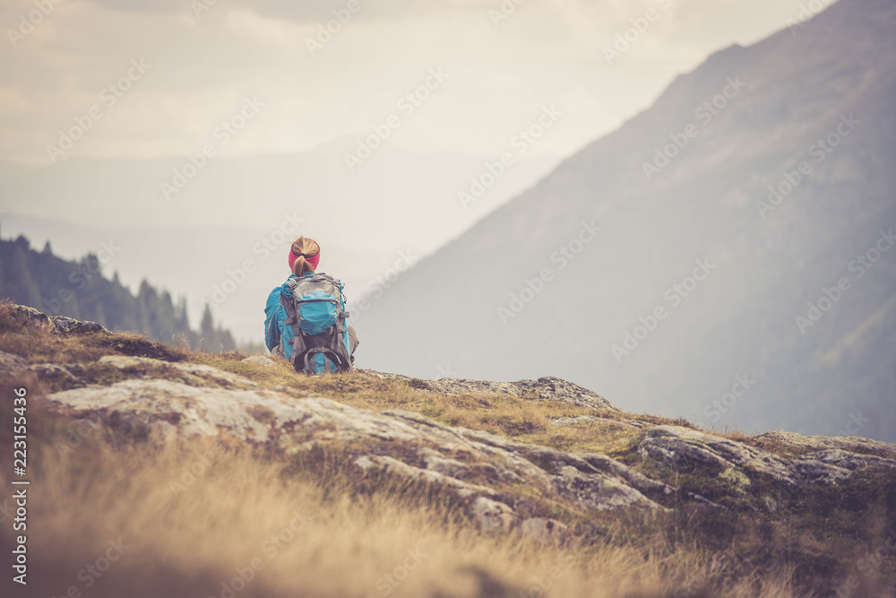 Junge blonde Frau sitzend in den Bergen, Blick in die Ferne, Abenteuer