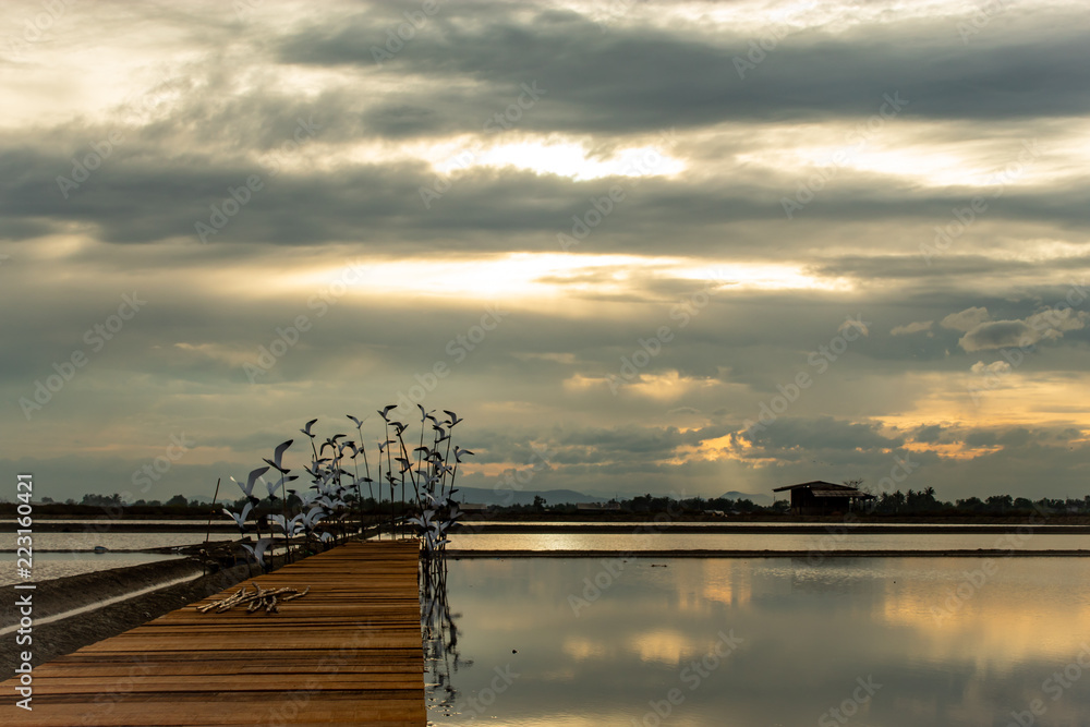 Sunset light reflects from the surface of the water and the wooden bridge.