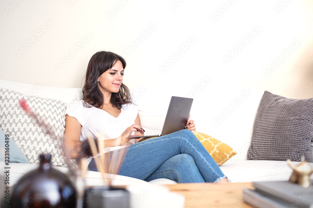 Young woman relaxing on a sofa with a laptop Young woman relaxing on a sofa with a laptop