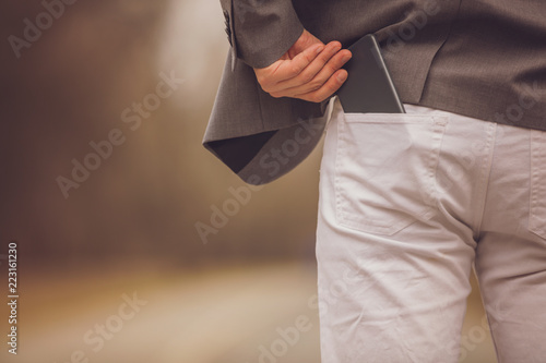 Modern business man holding cellphone in pocket.