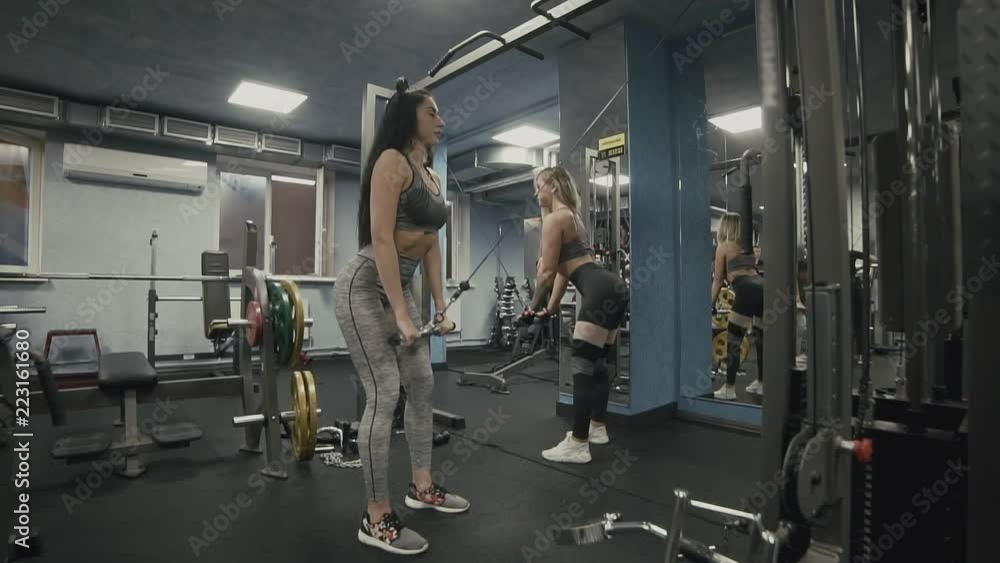 Girls doing exercise on back muscles in block simulator in slow motion. Wide angle Girls doing exercise on back muscles in block simulator in slow motion. Wide angle