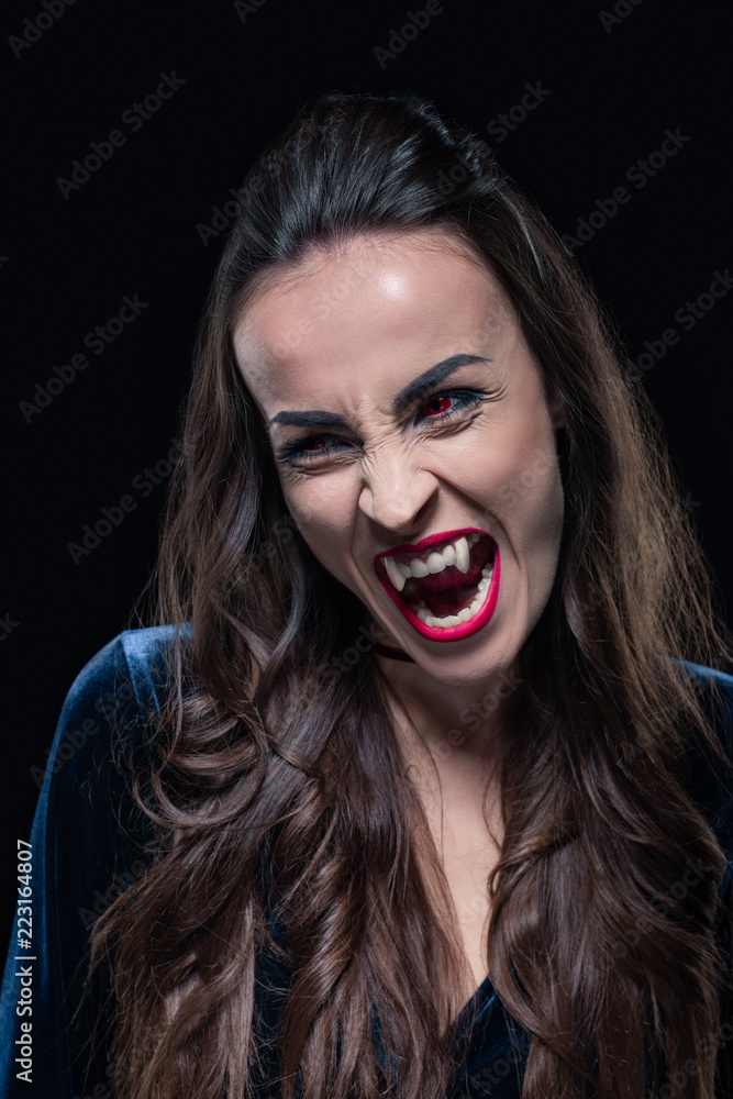 dreadful woman showing vampire teeth isolated on black