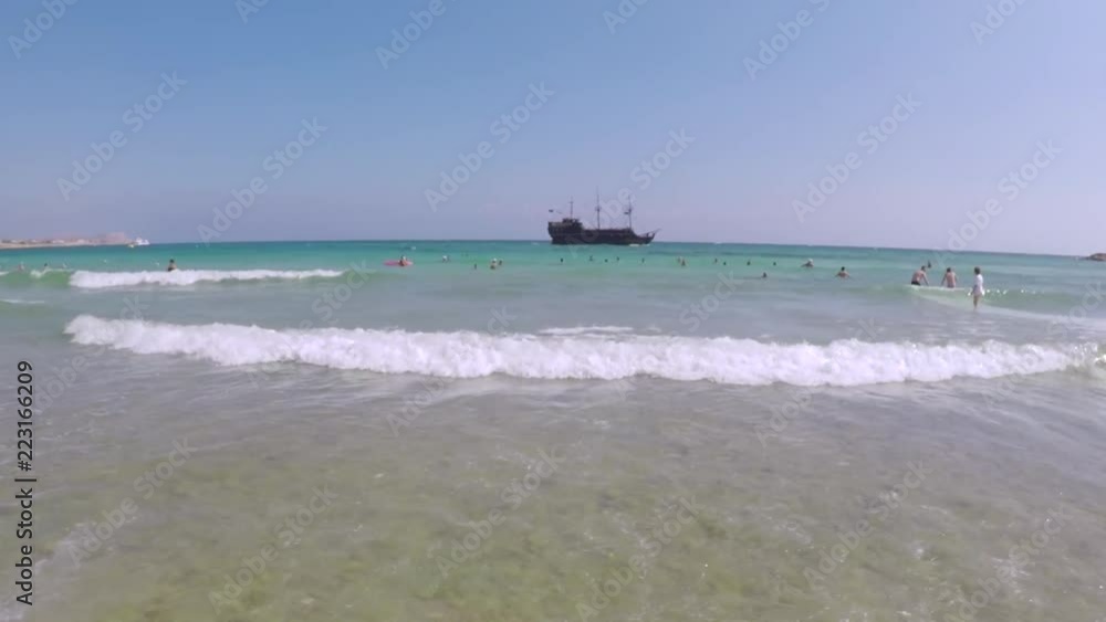 An ancient ship swims into the sea, view from the beach, waves beat against the shore An ancient ship swims into the sea, view from the beach, waves beat against the shore