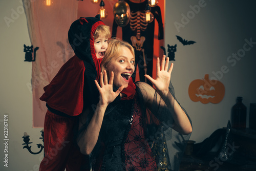 Halloween family party and funny people. Children play with mother and have fun. Mother flies with a child on Halloween background. Witch hat for mother and son.